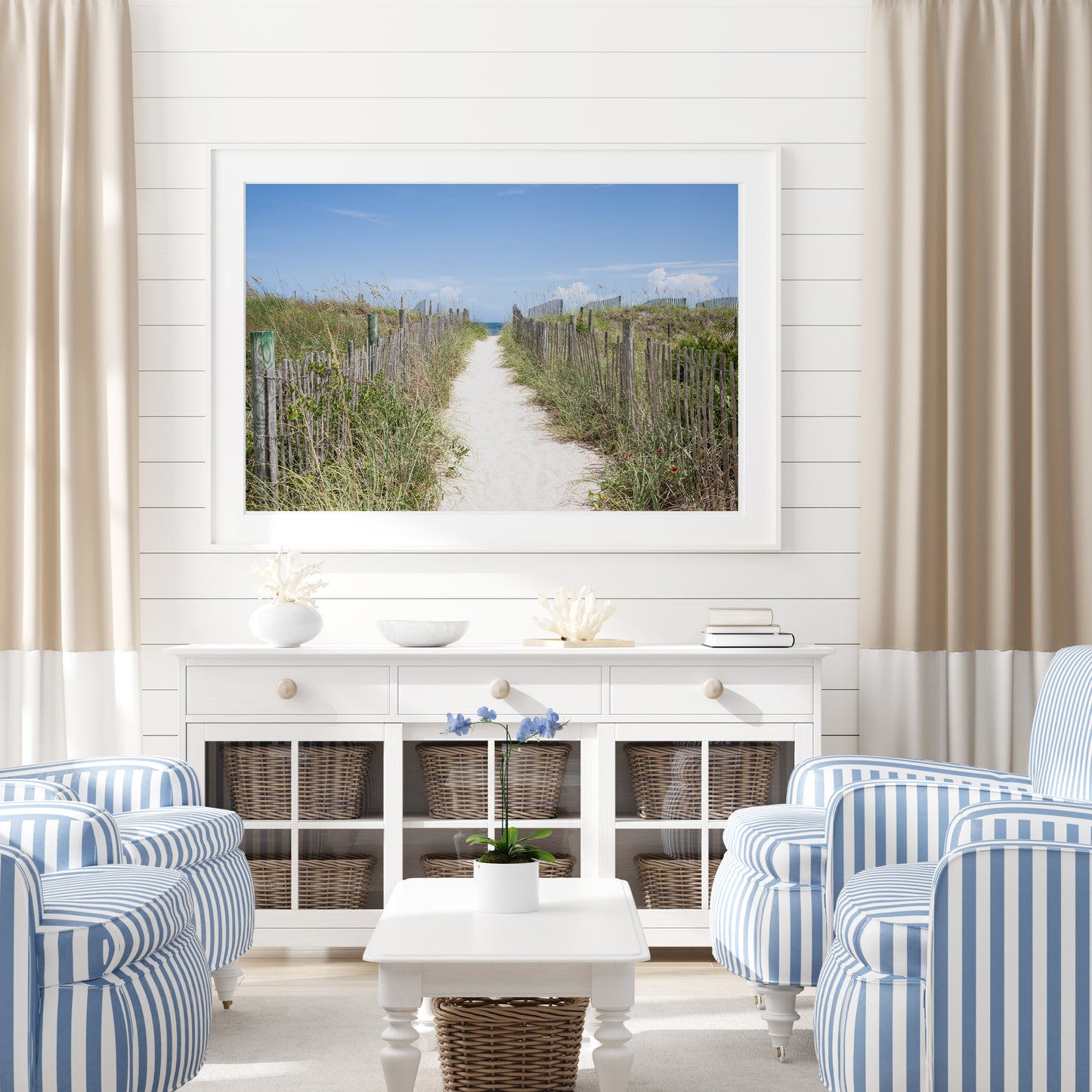 Living room with striped chairs, a coffee table, and a large framed picture of a beach path.