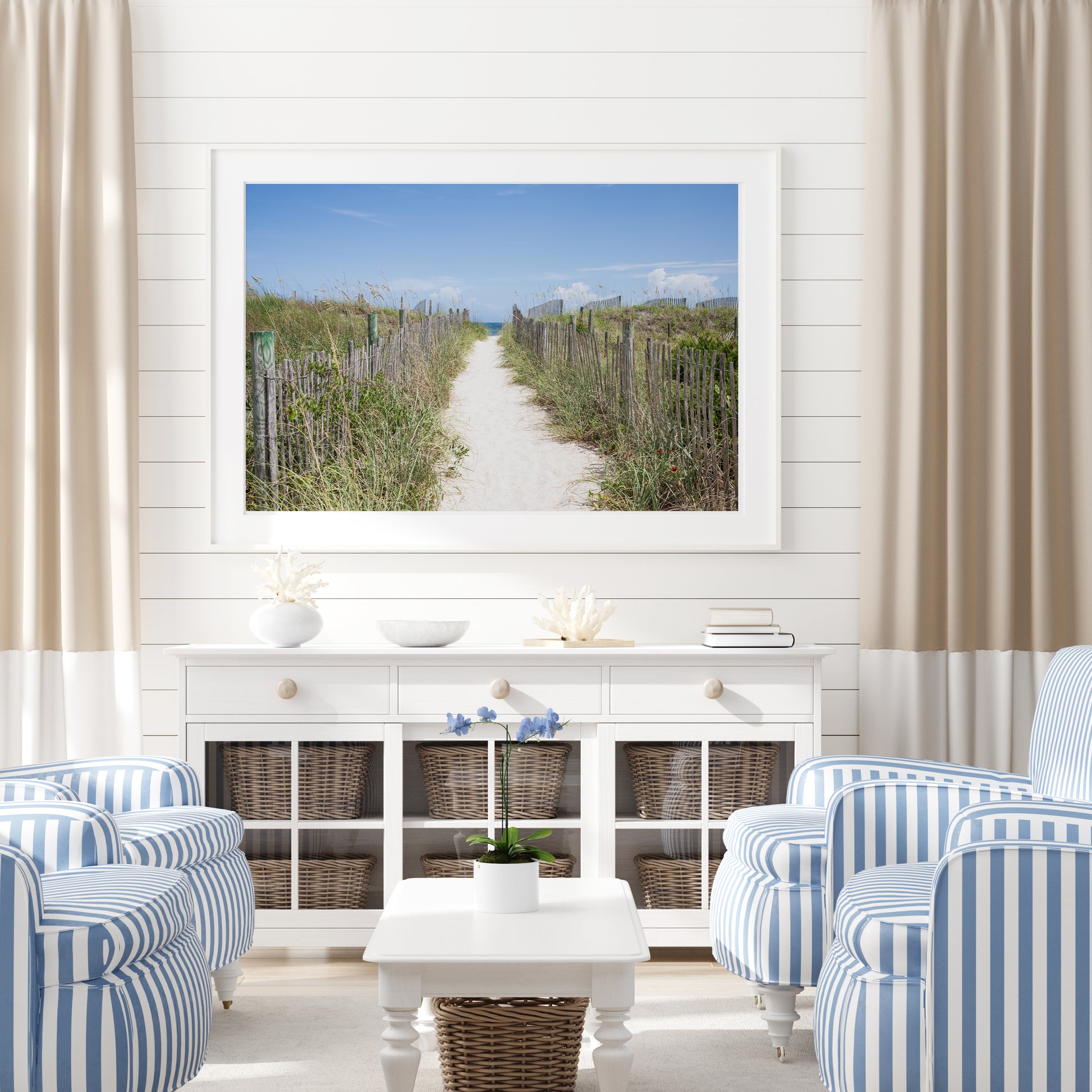 Living room with striped chairs, a coffee table, and a large framed picture of a beach path.