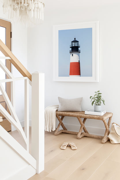 Color fine art photograph of Sankaty Head Lighthouse on Nantucket Island — red and white banded tower against a soft blue sky.