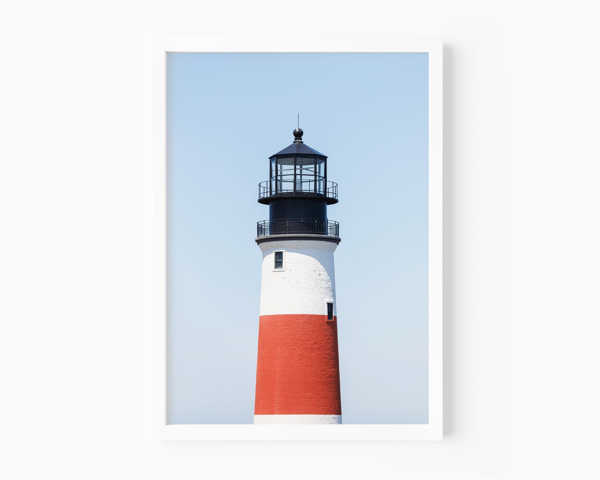 Color fine art photograph of Sankaty Head Lighthouse on Nantucket Island — red and white banded tower against a soft blue sky.