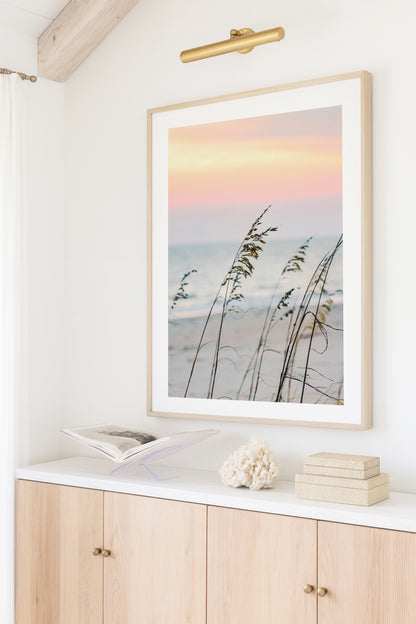 Color fine art photograph of sea oats swaying in the foreground against a soft pink and peach sunset over the Carolina coast — dreamy coastal beach wall art