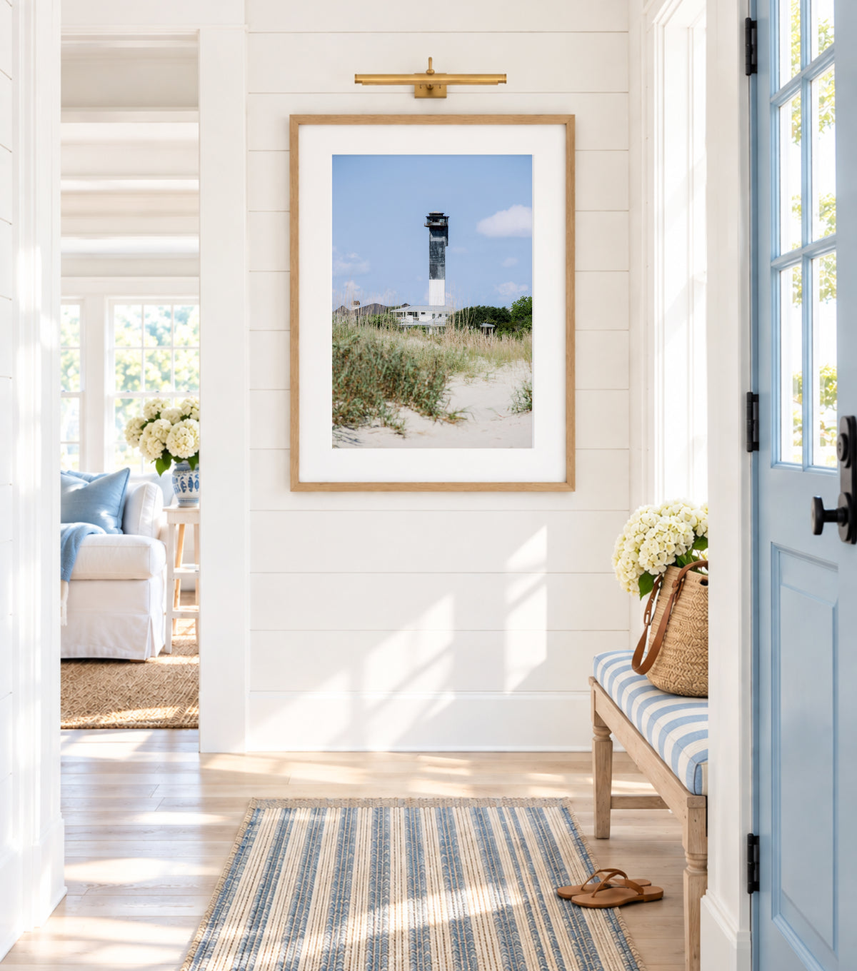 Color fine art photograph of the Edgartown Lighthouse on Martha's Vineyard, white tower centered against a pale blue sky with beach grass in the foreground and Edgartown village behind it