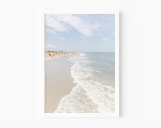 Vertical beach photograph of Tybee Island, Georgia with gentle ocean waves, soft sand, and scattered beachgoers on a bright summer day – coastal Georgia wall art.