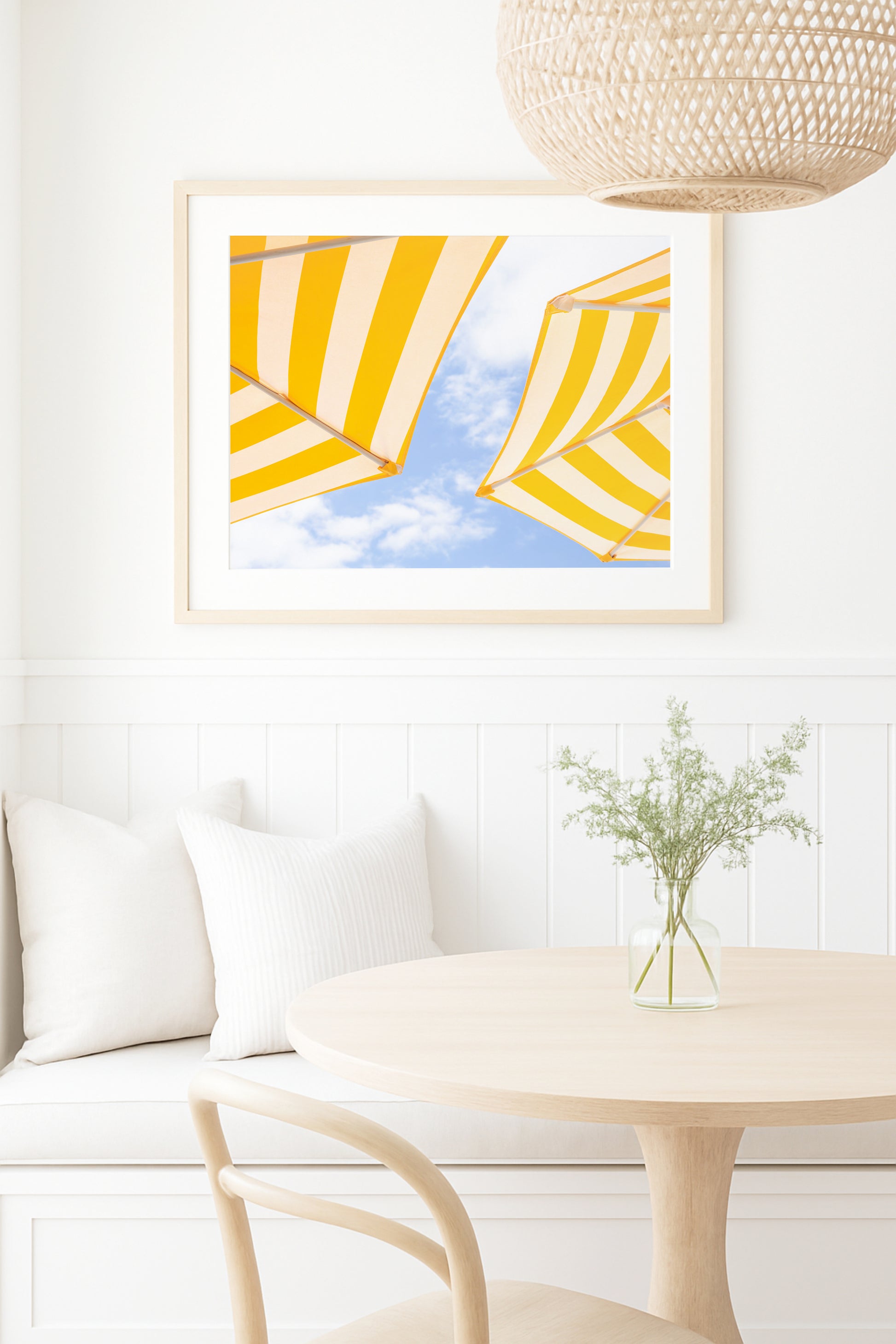 Yellow and white striped beach umbrellas set against a bright blue sky with scattered clouds; minimalist beach photography evoking a sunny coastal vibe.